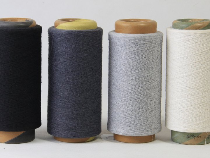 Quatre bobines de fil : noire, bleu marine, grise et blanche
